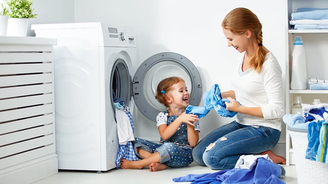 Child helping parent load a front loading washing machine